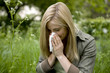 A young woman sitting on the grass, blowing her nose