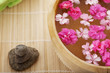 Spa therapy, flowers in water, on a bamboo mat.