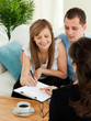 Bright young couple signing a contract sitting in their living r