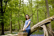 A young woman leaning against a tree, holding a picnic basket