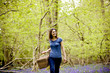 A young woman walking through the woods, holding a picnic basket