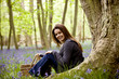 A young woman sitting under a tree, holding a picnic basket