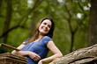 A young woman leaning against a tree, holding a picnic basket