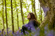 A young woman sitting under a tree, smiling