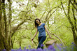 A young woman walking through the woods, holding a picnic basket