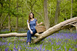 A young woman sitting on a tree, holding a picnic basket