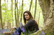 A young woman sitting under a tree, holding a picnic basket