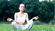 Woman sitting on the grass in park and meditating, dolly shot