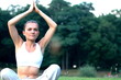 Woman sitting on the grass in park and meditating, dolly shot