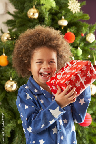 Photo: Young Boy Holding Gift In Front Of Christmas Tree Young Boy Holding Gift In Front Of Christmas Tree