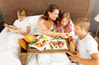 Photo: family having breakfast in bed - boy reading newspaper family having breakfast in bed - boy reading newspaper