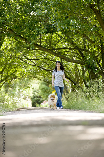 Foto: A young woman walking her dog in summertime A young woman walking her dog in summertime