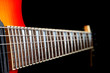 A six string electric guitar neck isolated on a black background