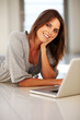An attractive young woman lying on floor using a laptop