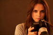 Beautiful young lady with a camera against brown background Beautiful young lady with a camera against brown background