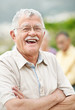 Photo: Relaxed old man laughing outdoors with people in background Relaxed old man laughing outdoors with people in background