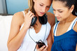 Young female friends listening to music on mobile phone