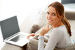 Happy woman sitting on couch with a laptop