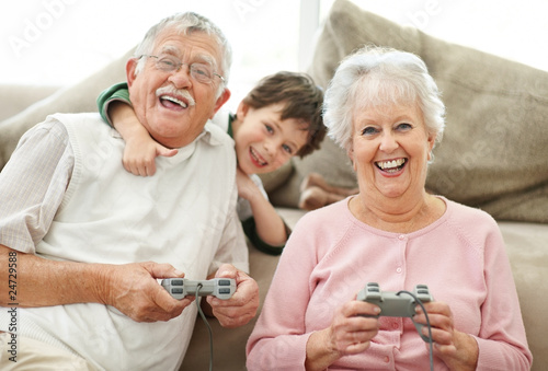 Photo: Grandparents and little boy having fun playing video games Grandparents and little boy having fun playing video games