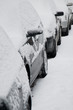 Bunch of snow covered cars  standing in a row
