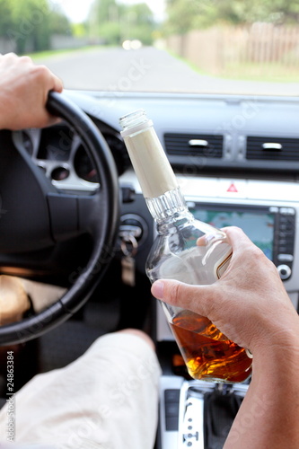 Photo: Drunk driver on a rural road with a bottle of alcohol in hand Drunk driver on a rural road with a bottle of alcohol in hand