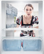 Young woman looking on empty shelf in fridge