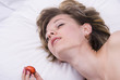 Young woman lying down with sex toys on a bed