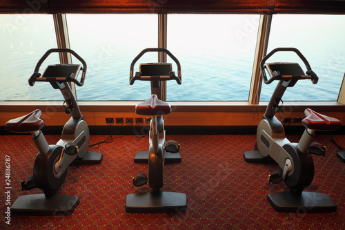 Photo: large gym hall with exercise bicycle near window large gym hall with exercise bicycle near window