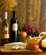 Wine, grapes in a basket and cheese variates on a cheeseboard