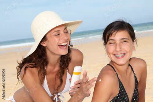 Photo: Mother spreading sunscreen on her daughter's shoulders Mother spreading sunscreen on her daughter's shoulders