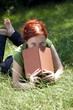 jeune femme détendue couchée dans l'herbe avec un livre