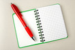Opened notebook squared pagewith red pen over it on grey backgro
