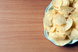 Potato chips in plate on wood table