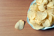 Potato chips in plate on wood table