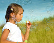 Sumer wishes, little girl blowing soap bubbles at sunset
