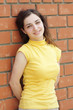 Young woman leaning on brick wall