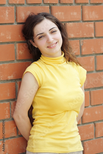 Photo: Young woman leaning on brick wall Young woman leaning on brick wall