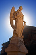 Marble angel statue backlit with blue sky and mountain