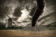 Zoom of a large tornado over a wind mill