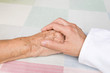 Foto: hand of a doctor holding the hand of an elderly patient hand of a doctor holding the hand of an elderly patient