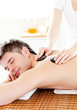 Happy young man enjoying a back massage with hot stone Happy young man enjoying a back massage with hot stone