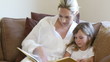 mother and daughter reading together sitting in the sofa