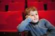 boy sitting on armchairs at cinema, steadfastly looking