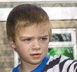 Candid close up portrait of a cute six year old boy looking worr