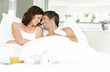 Relaxed couple lying on bed with breakfast in foreground Relaxed couple lying on bed with breakfast in foreground