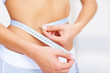 Fit young woman measuring her waistline