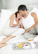 Happy mature couple having breakfast in bed