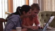 couple at home working on laptop sitting in the dining room