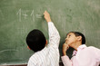 Two boys in classroom thinking, writing Two boys in classroom thinking, writing