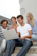 Friends sitting in stairs with laptop computer Friends sitting in stairs with laptop computer